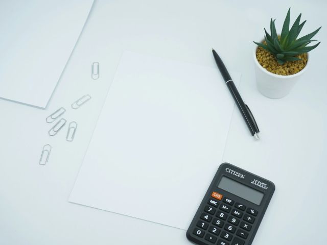 Desk calculator pen Tidy white desk with a calculator, pen and paper