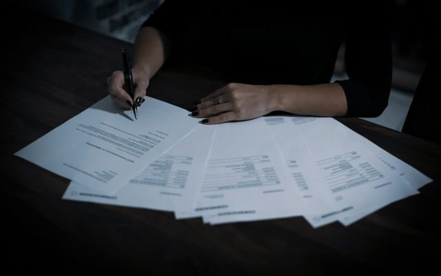 Signing loan documents Woman signing loan documents at a table spread with paperwork