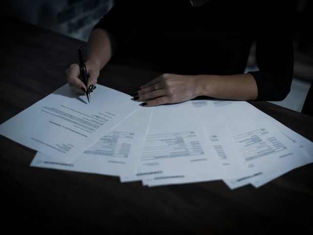 Signing loan documents Woman signing loan documents at a table spread with paperwork